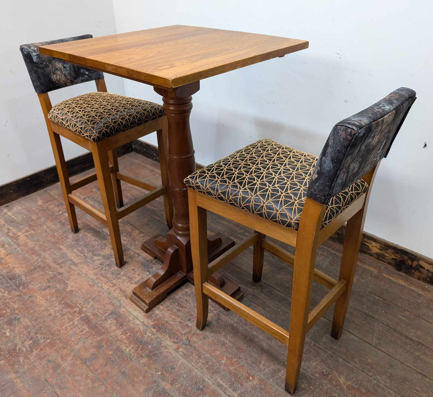 Tall Square Poseur Table with Two Patterned Bar Stools and Light Wood Finish
