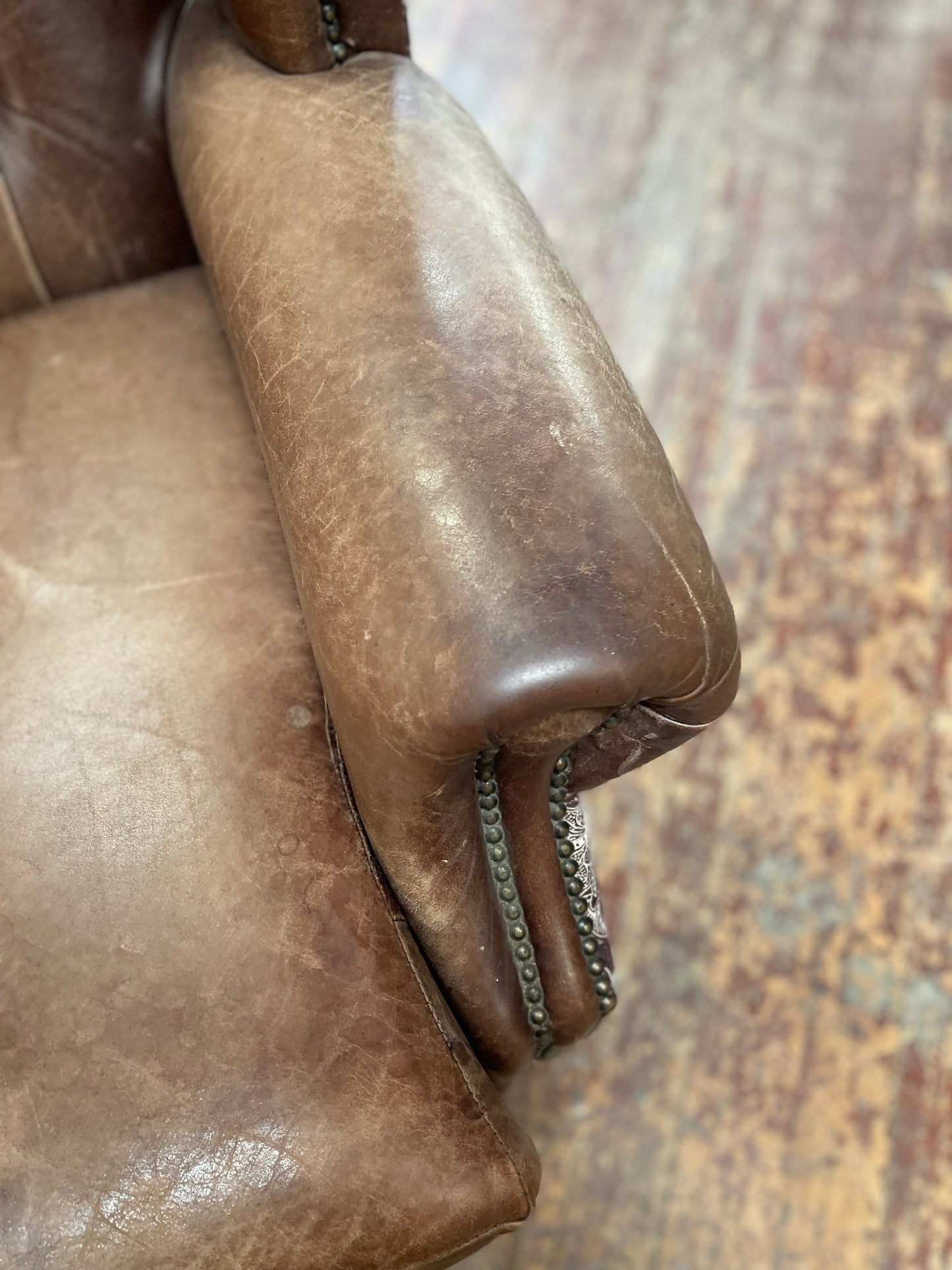 Brown leather wingback armchair with patterned fabric back and sides