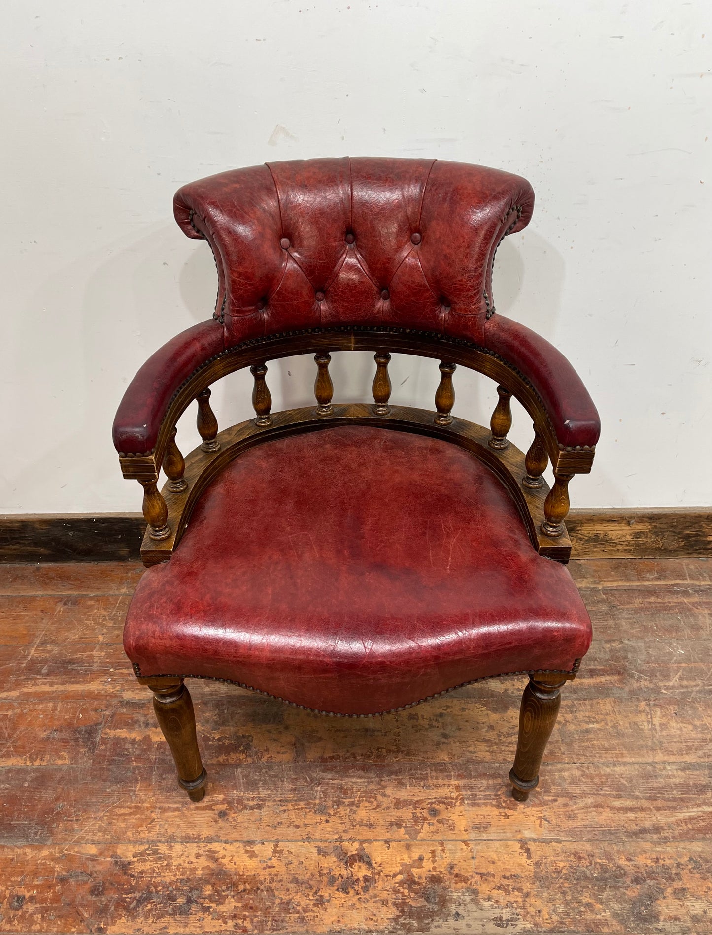 Stunning red leather captain's chair with wooden spindle back