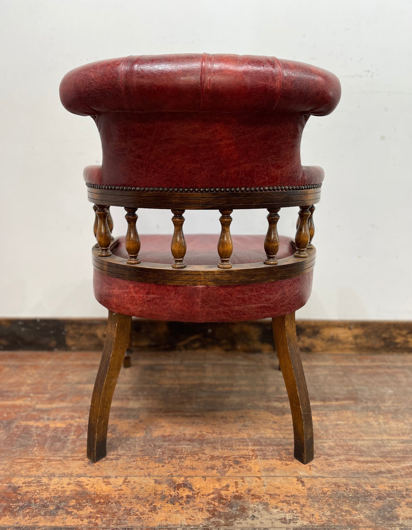 Stunning red leather captain's chair with wooden spindle back