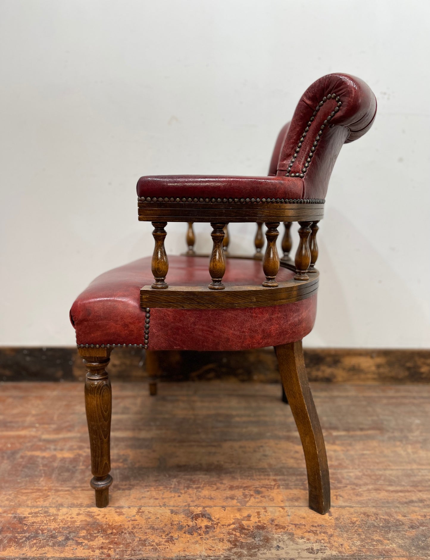 Stunning red leather captain's chair with wooden spindle back