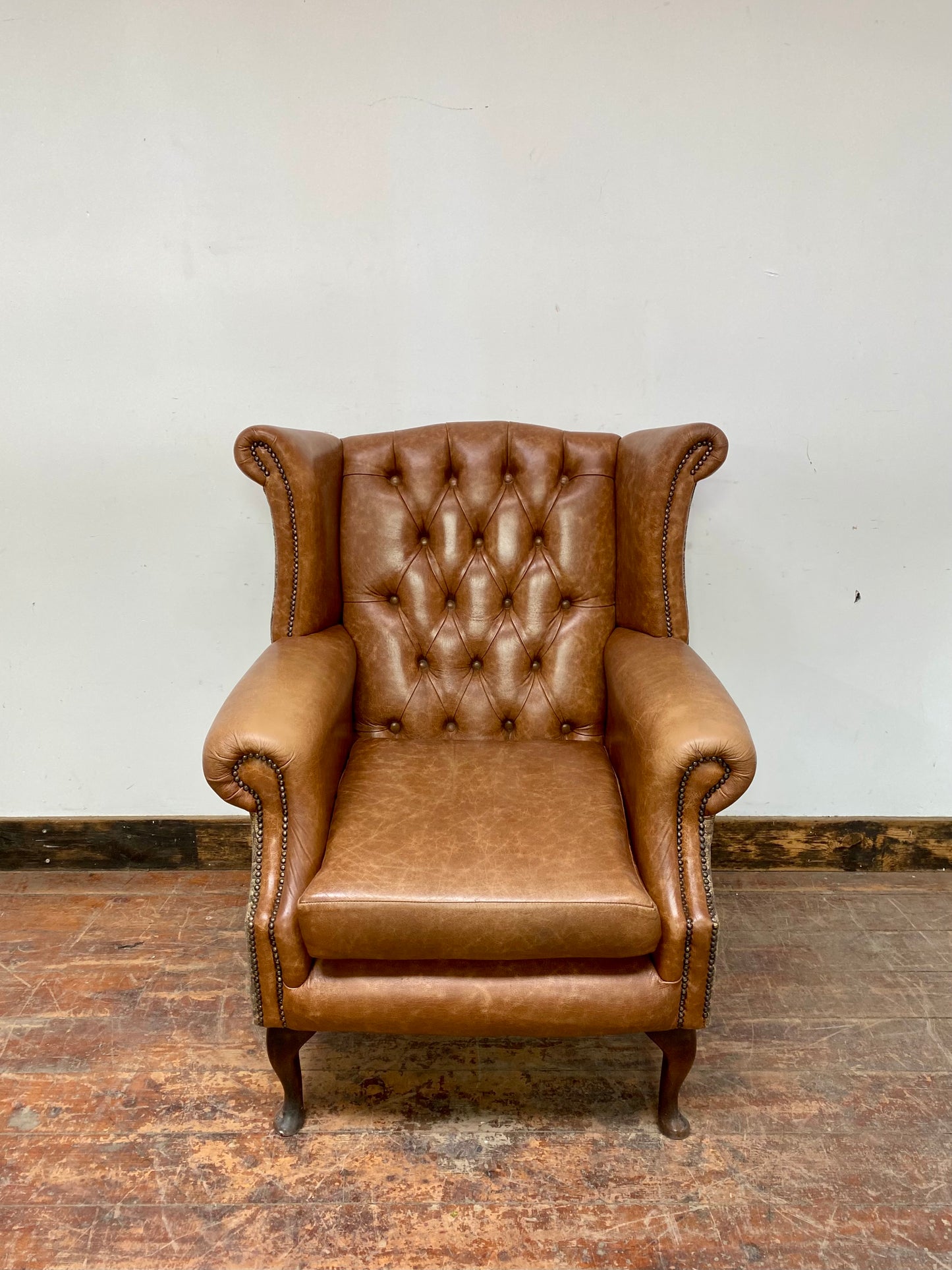 Tan leather wingback chair with patterned back