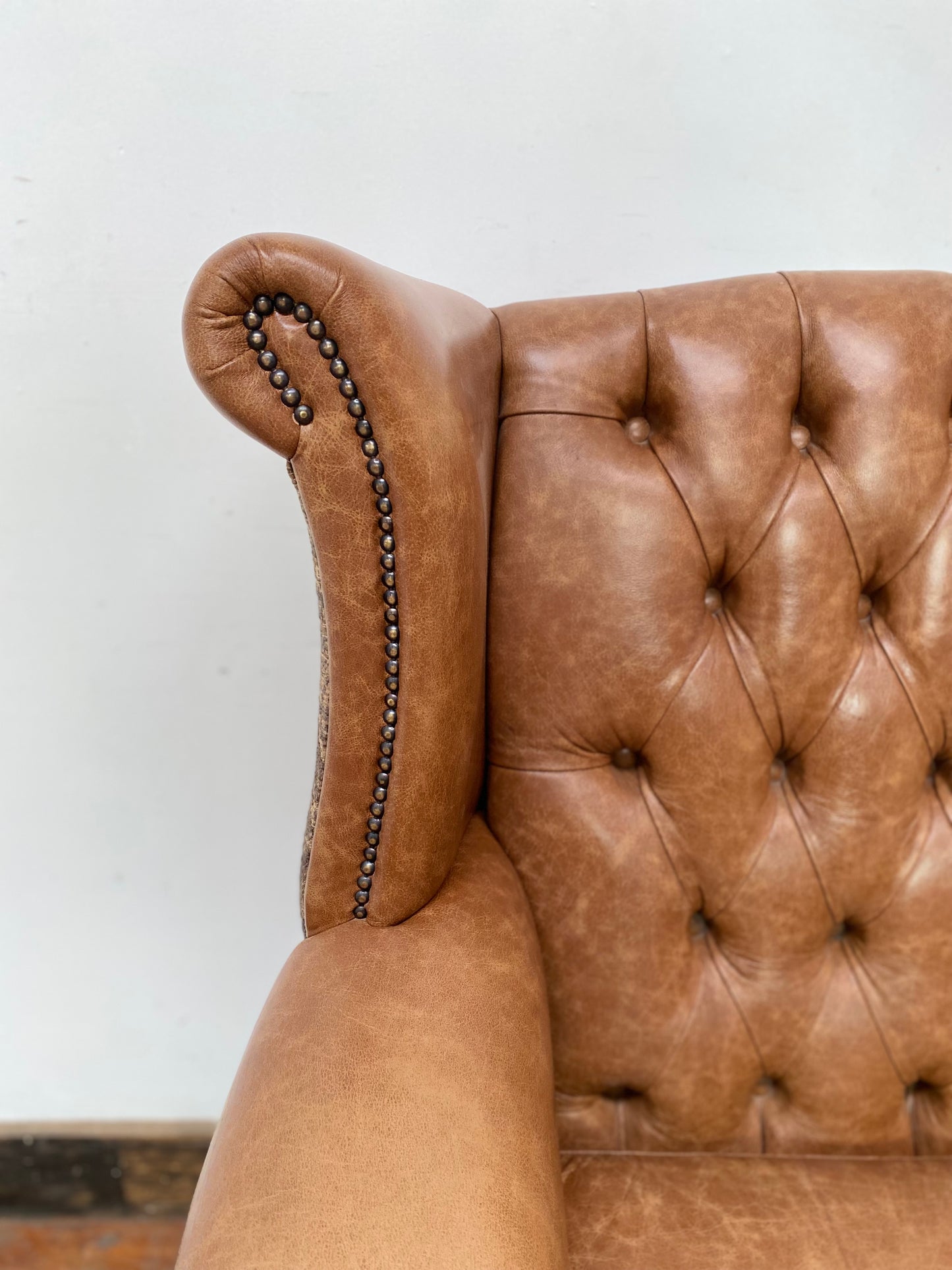 Tan leather wingback chair with patterned back