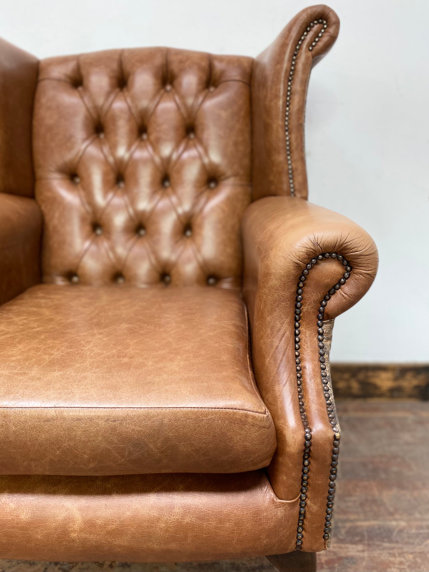 Tan leather wingback chair with patterned back