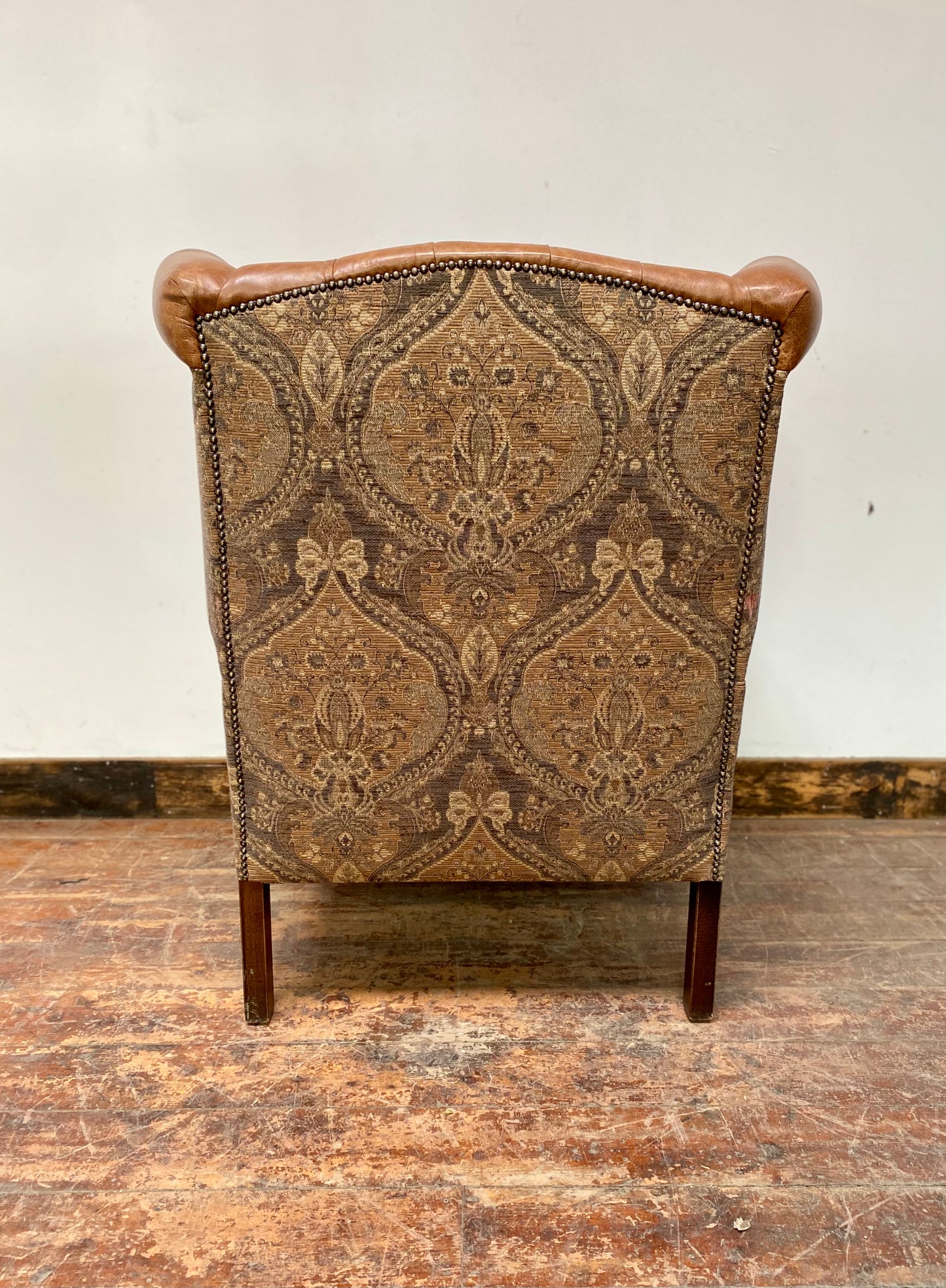 Tan leather wingback chair with patterned back