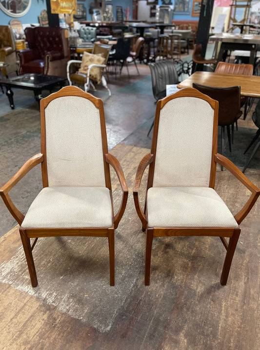 Pair of dining chairs with armrests and light fabric upholstery