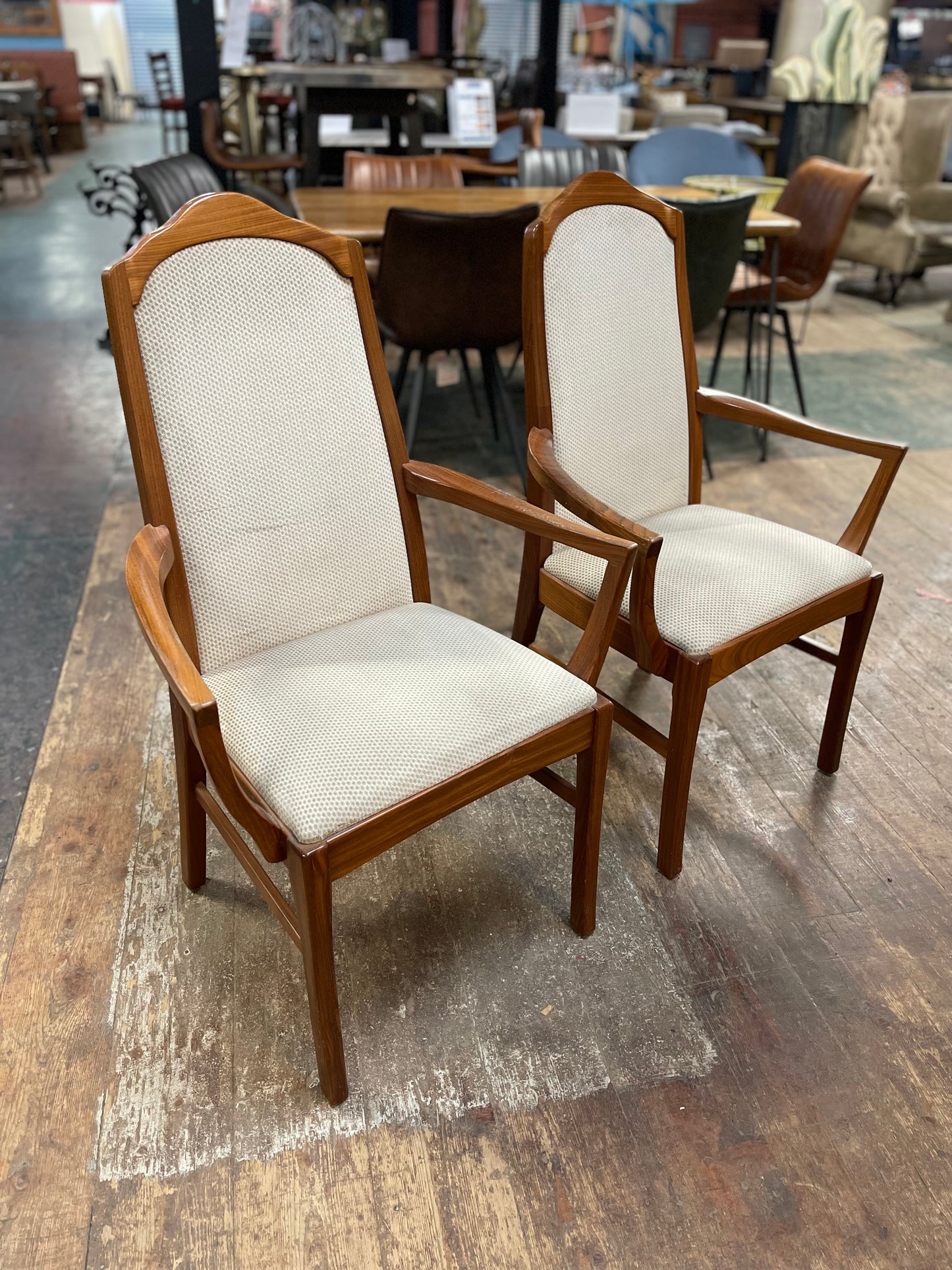 Pair of dining chairs with armrests and light fabric upholstery