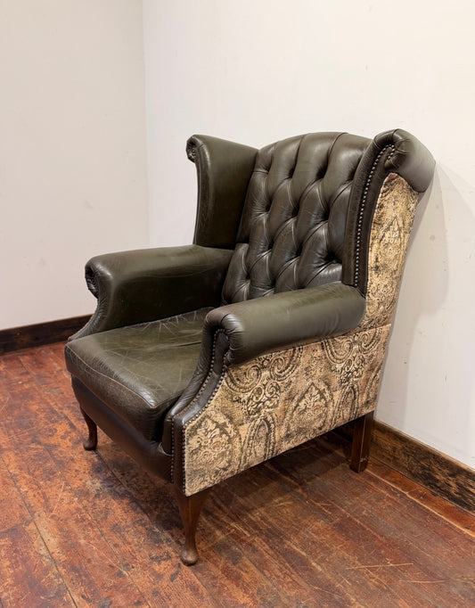 Stylish wingback armchair in dark green leather with fabric back