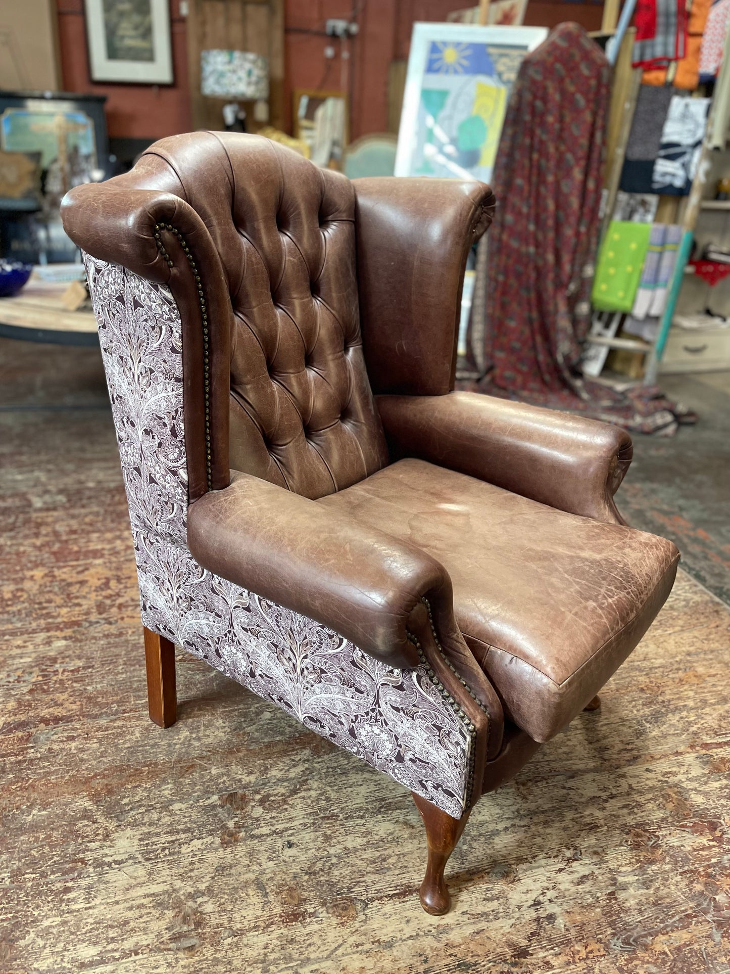 Brown leather wingback armchair with patterned fabric back and sides