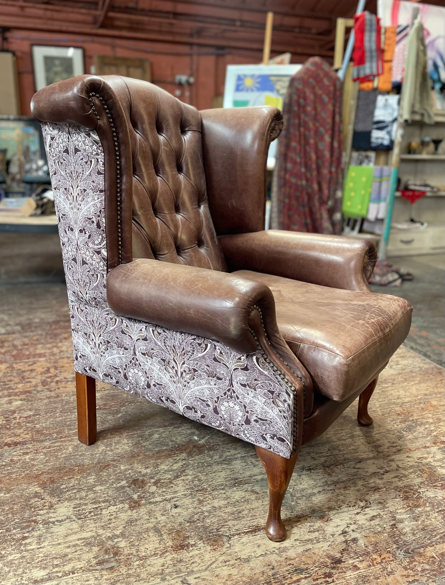 Brown leather wingback armchair with patterned fabric back and sides