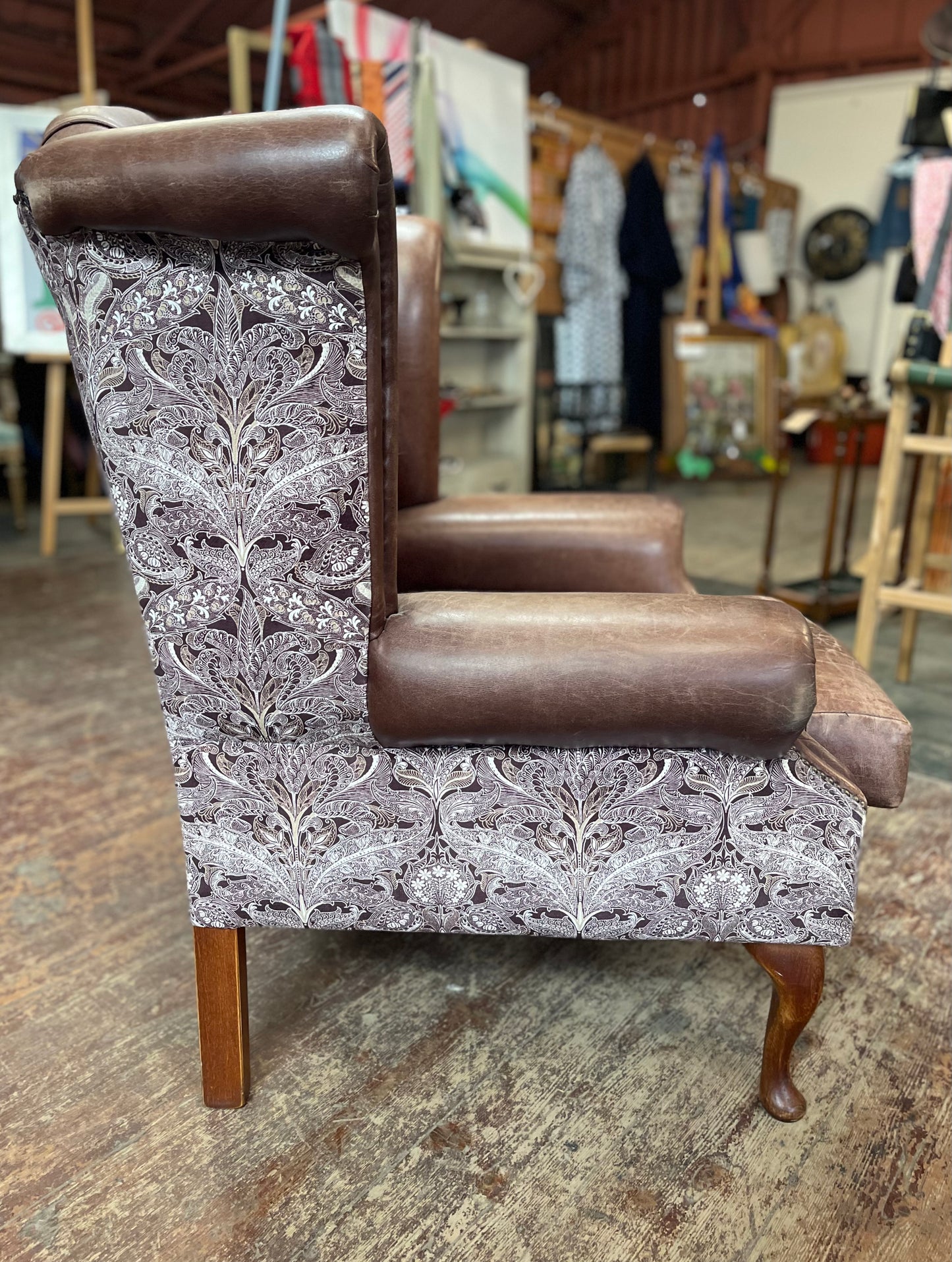Brown leather wingback armchair with patterned fabric back and sides