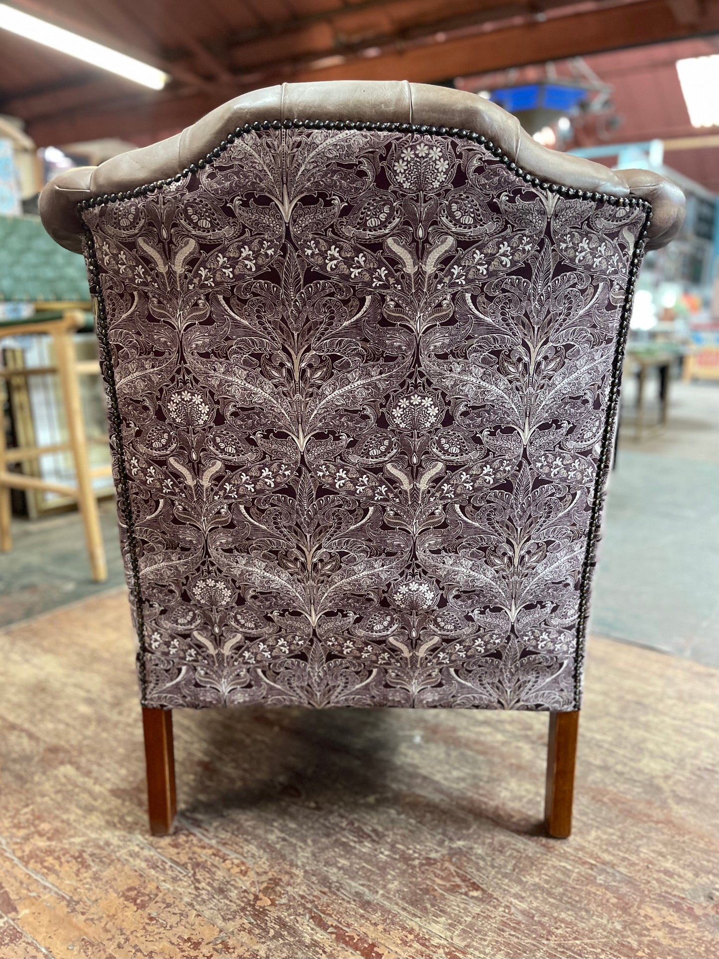 Brown leather wingback armchair with patterned fabric back and sides