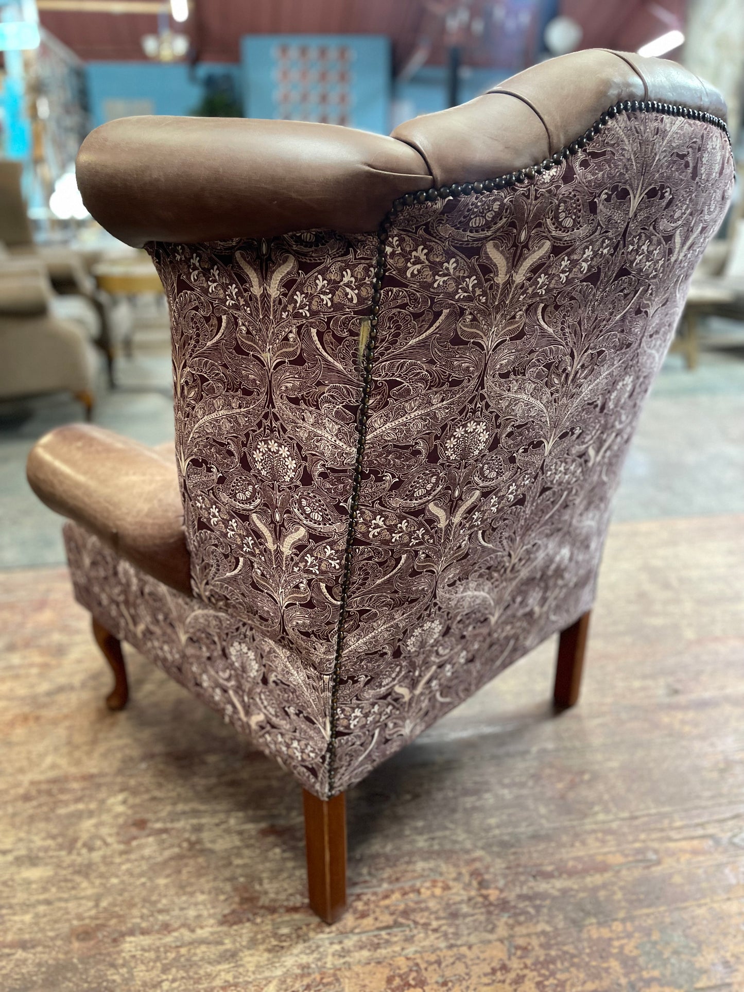 Brown leather wingback armchair with patterned fabric back and sides