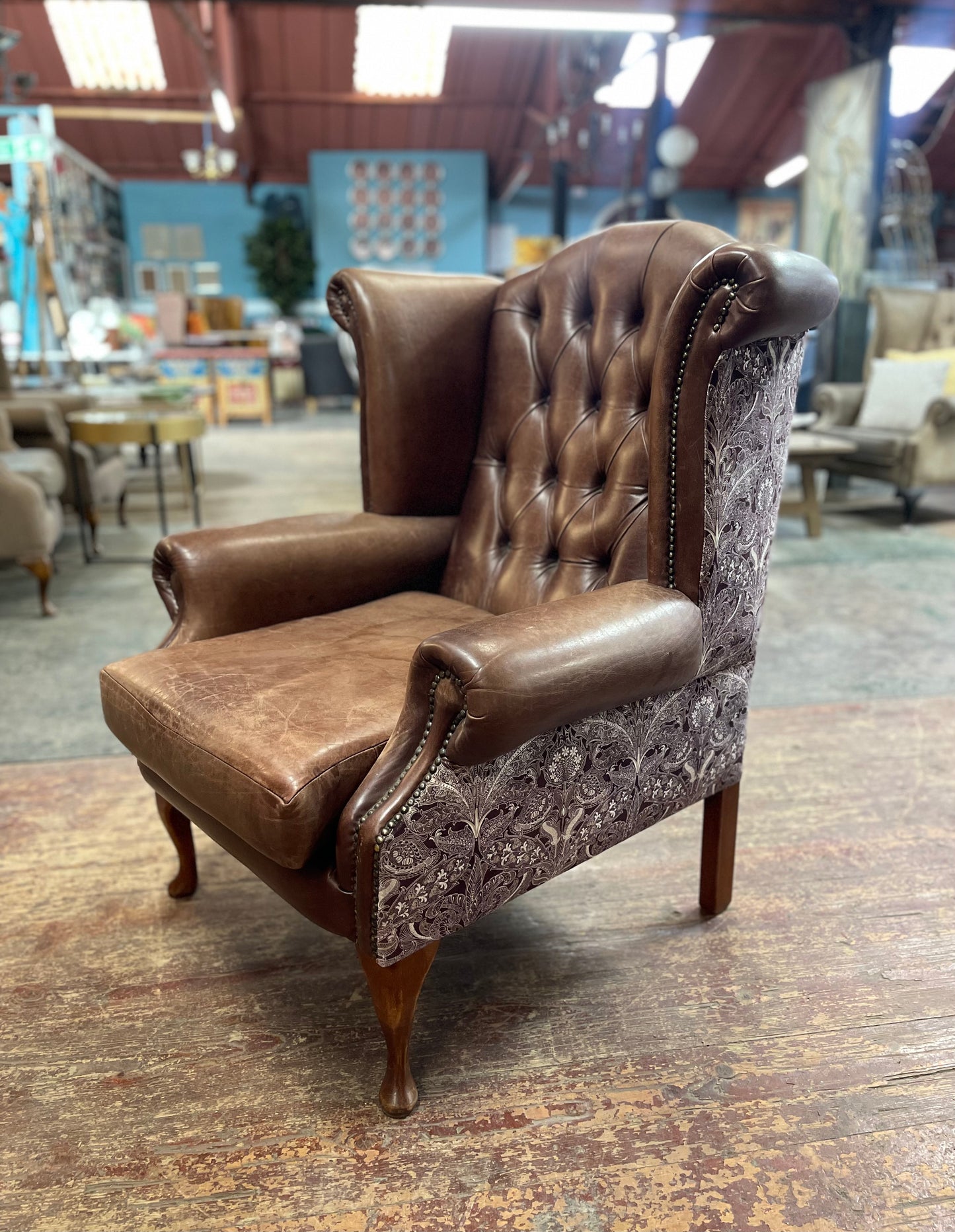 Brown leather wingback armchair with patterned fabric back and sides