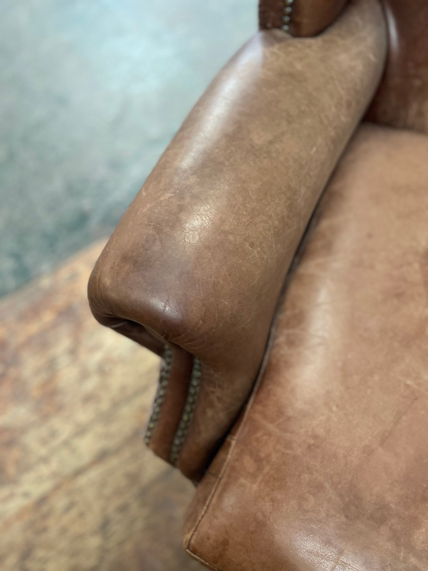 Brown leather wingback armchair with patterned fabric back and sides