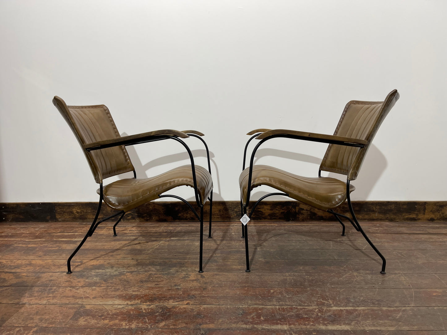 Pair of tan leather armchairs with metal frame
