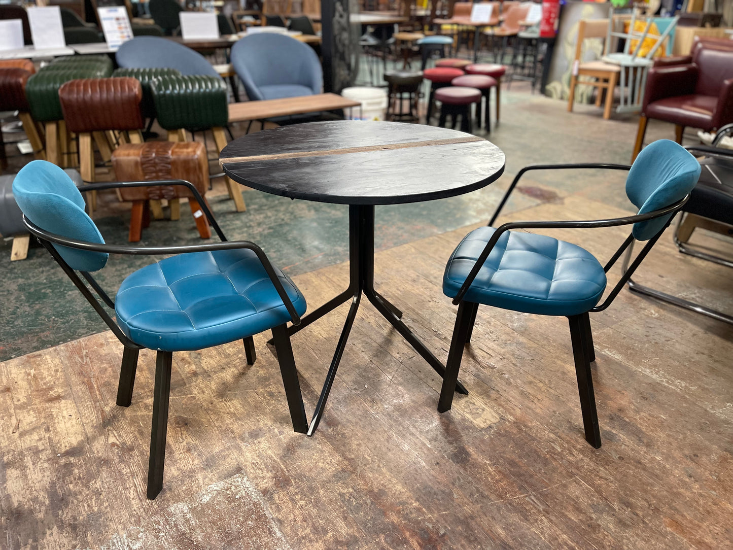 Pair of blue faux-leather chairs and black round table