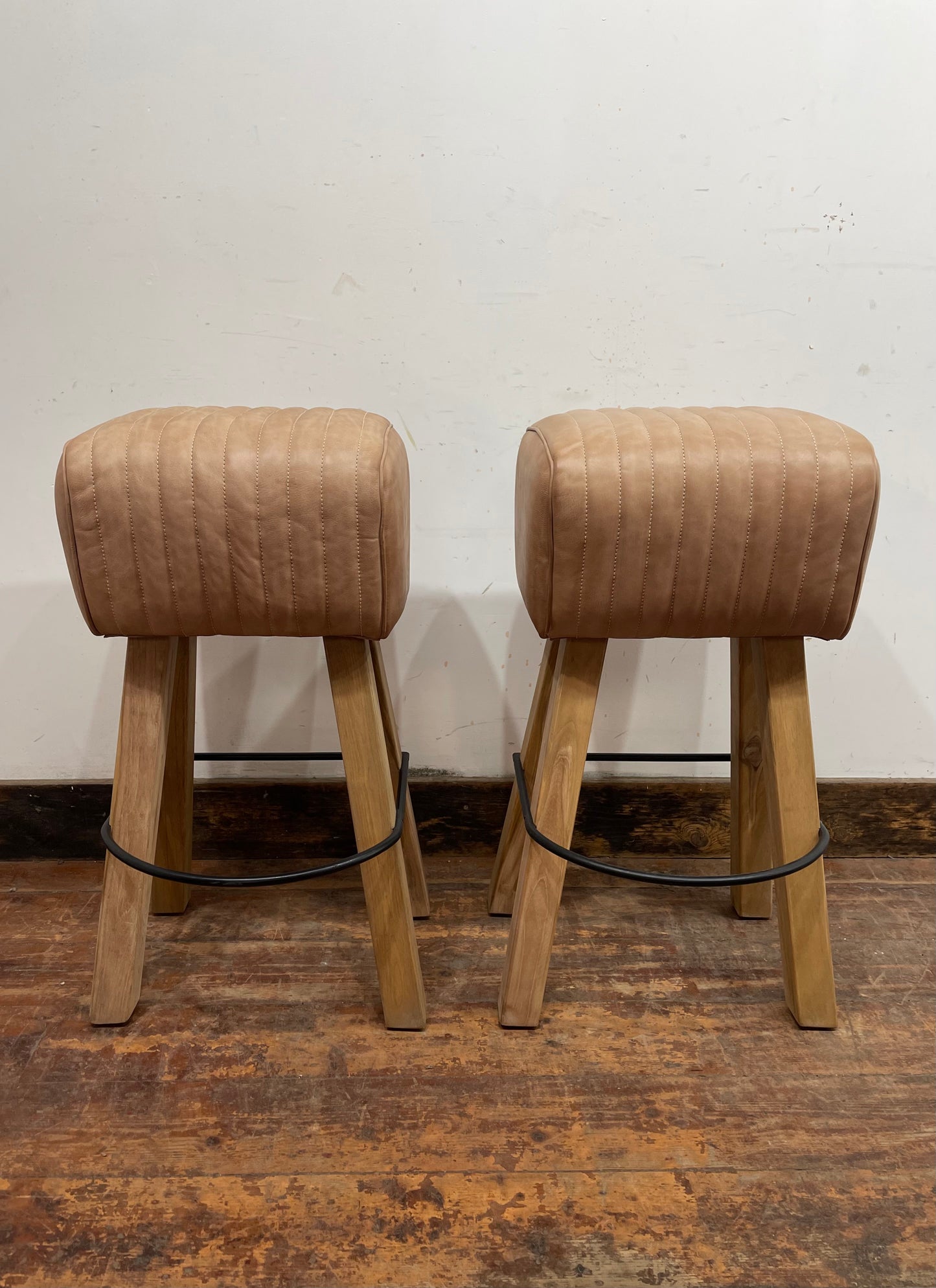 Pair of pommel stools with light tan leather seats