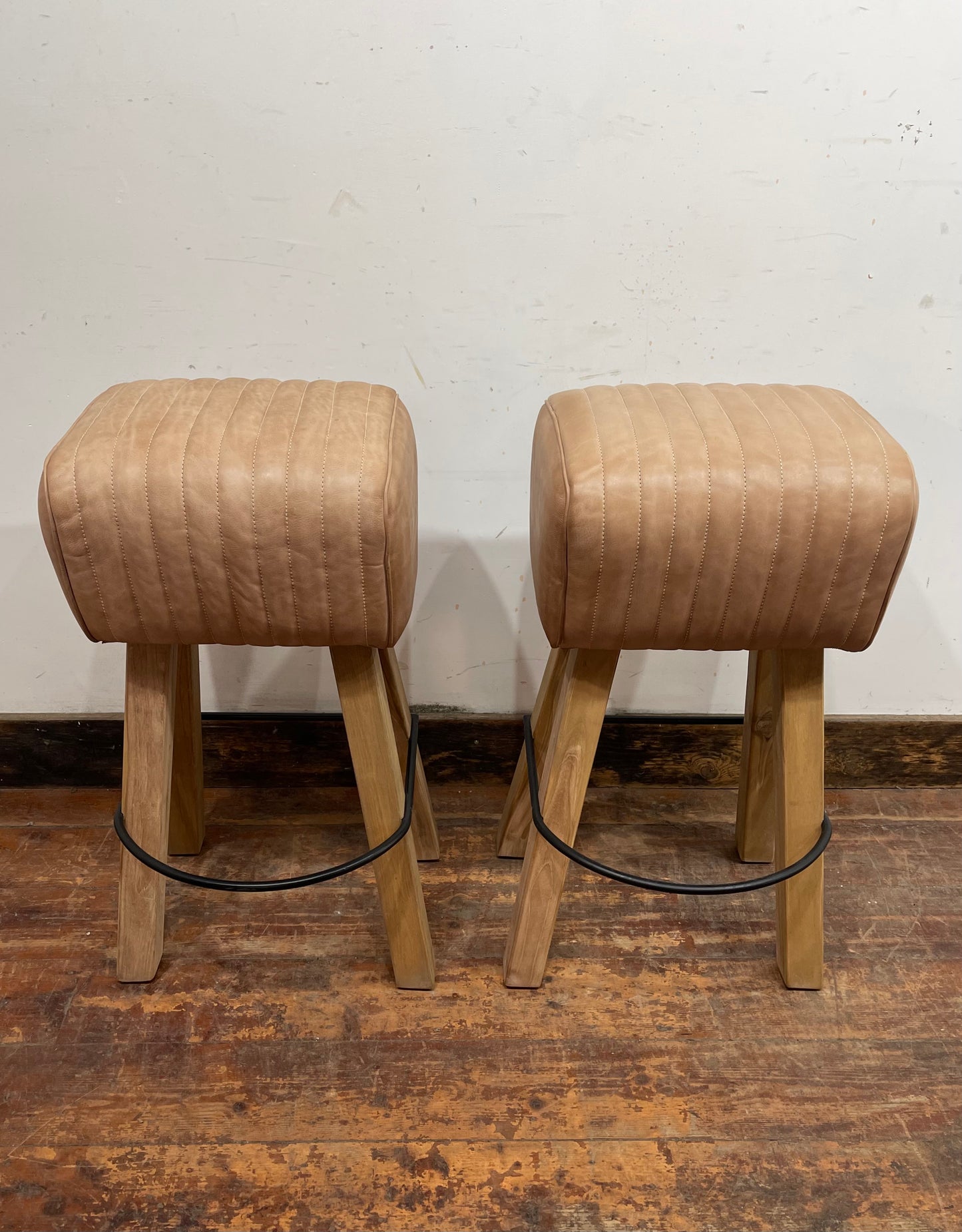 Pair of pommel stools with light tan leather seats