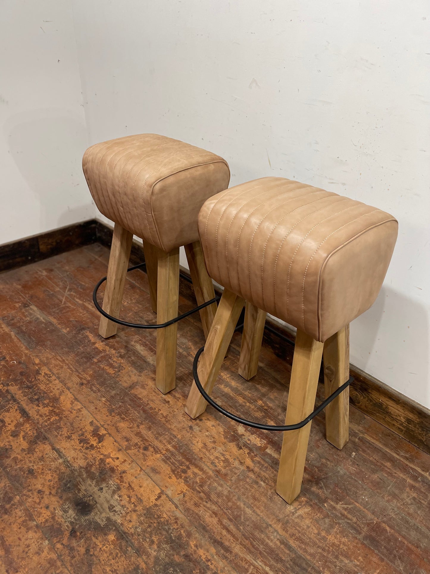 Pair of pommel stools with light tan leather seats