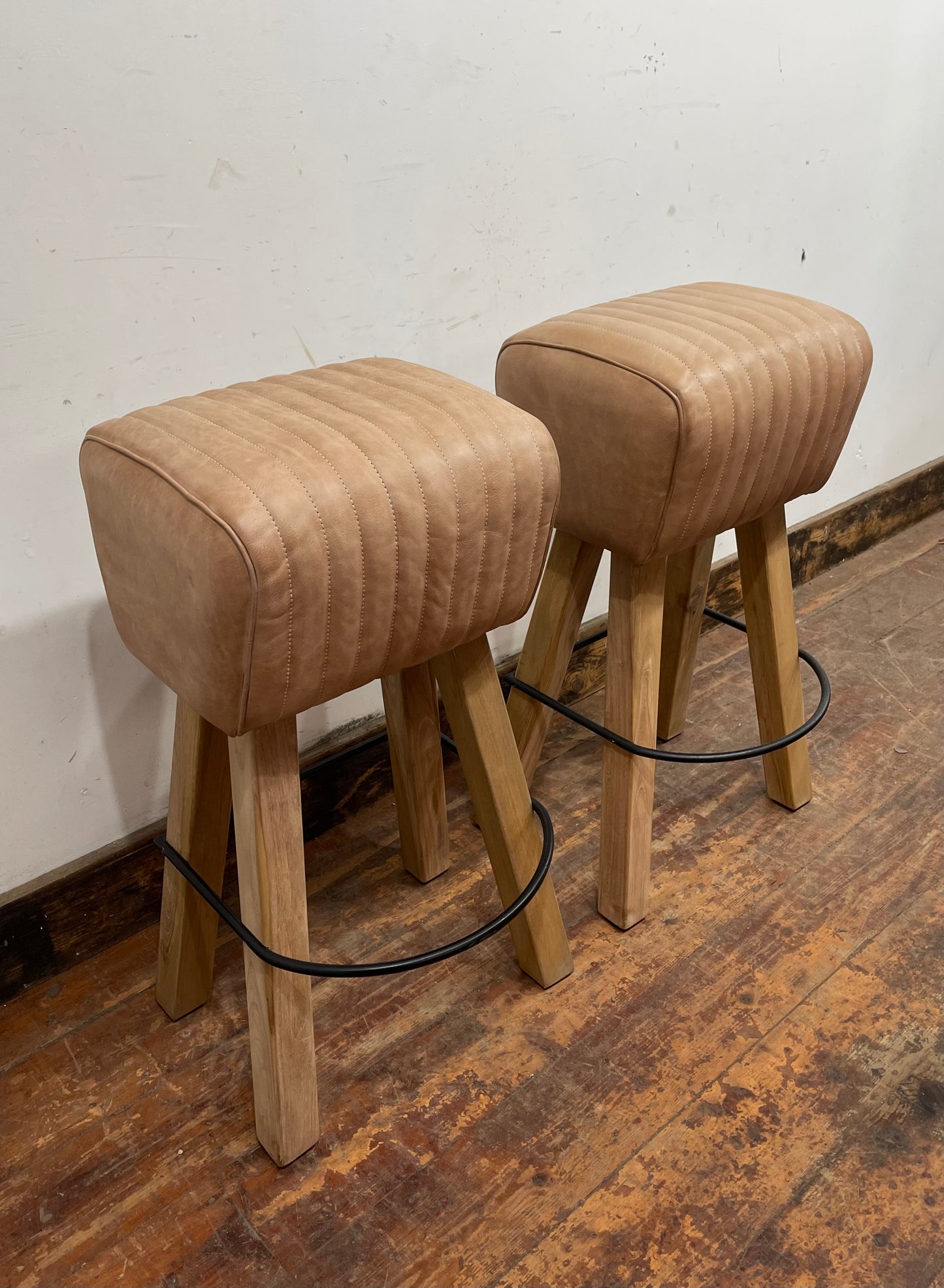 Pair of pommel stools with light tan leather seats