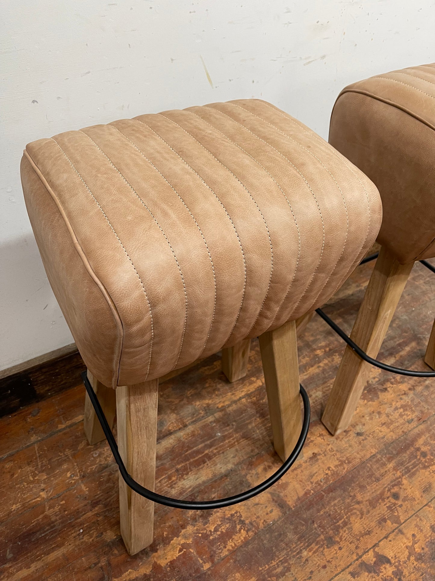 Pair of pommel stools with light tan leather seats