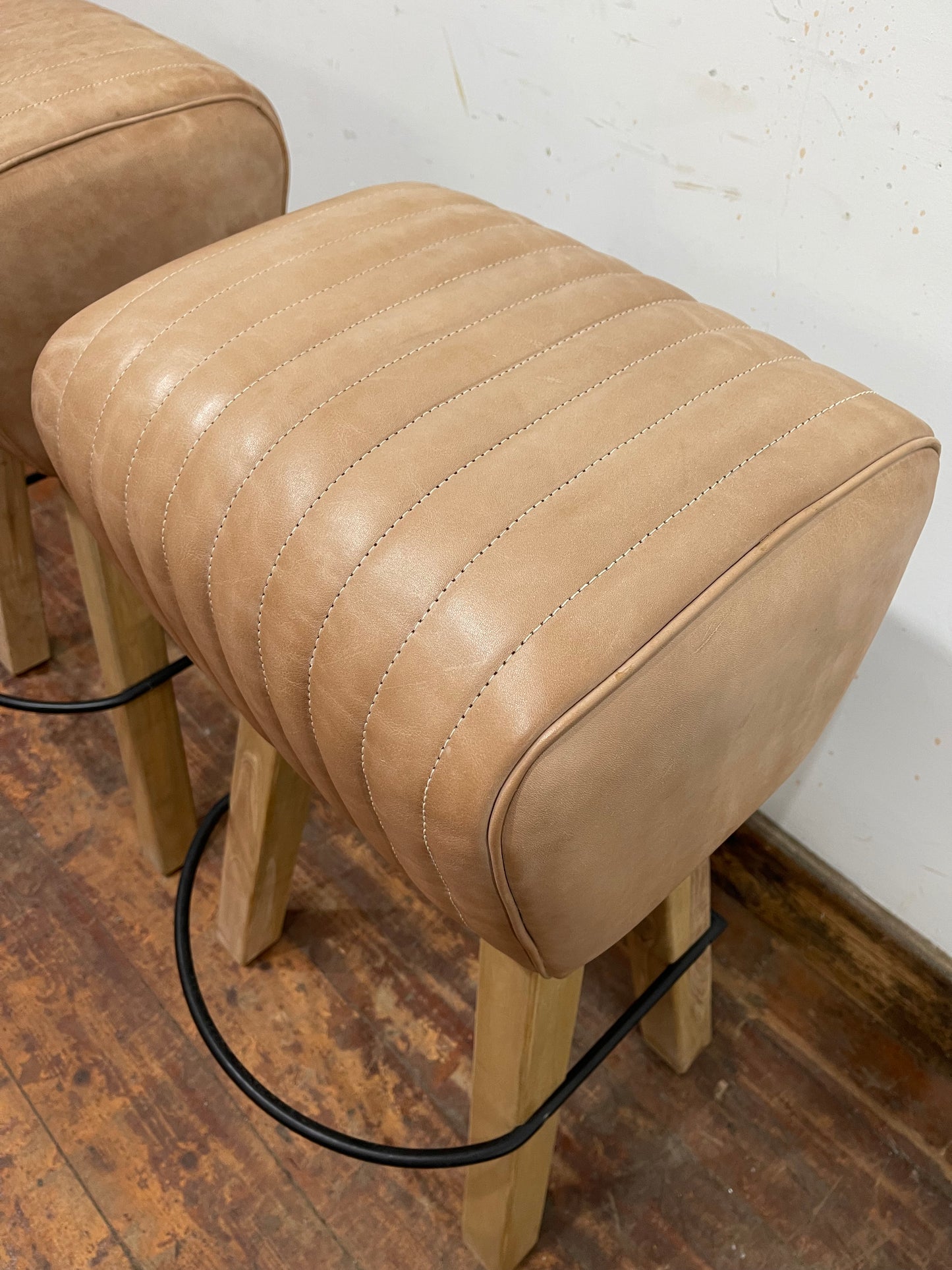 Pair of pommel stools with light tan leather seats