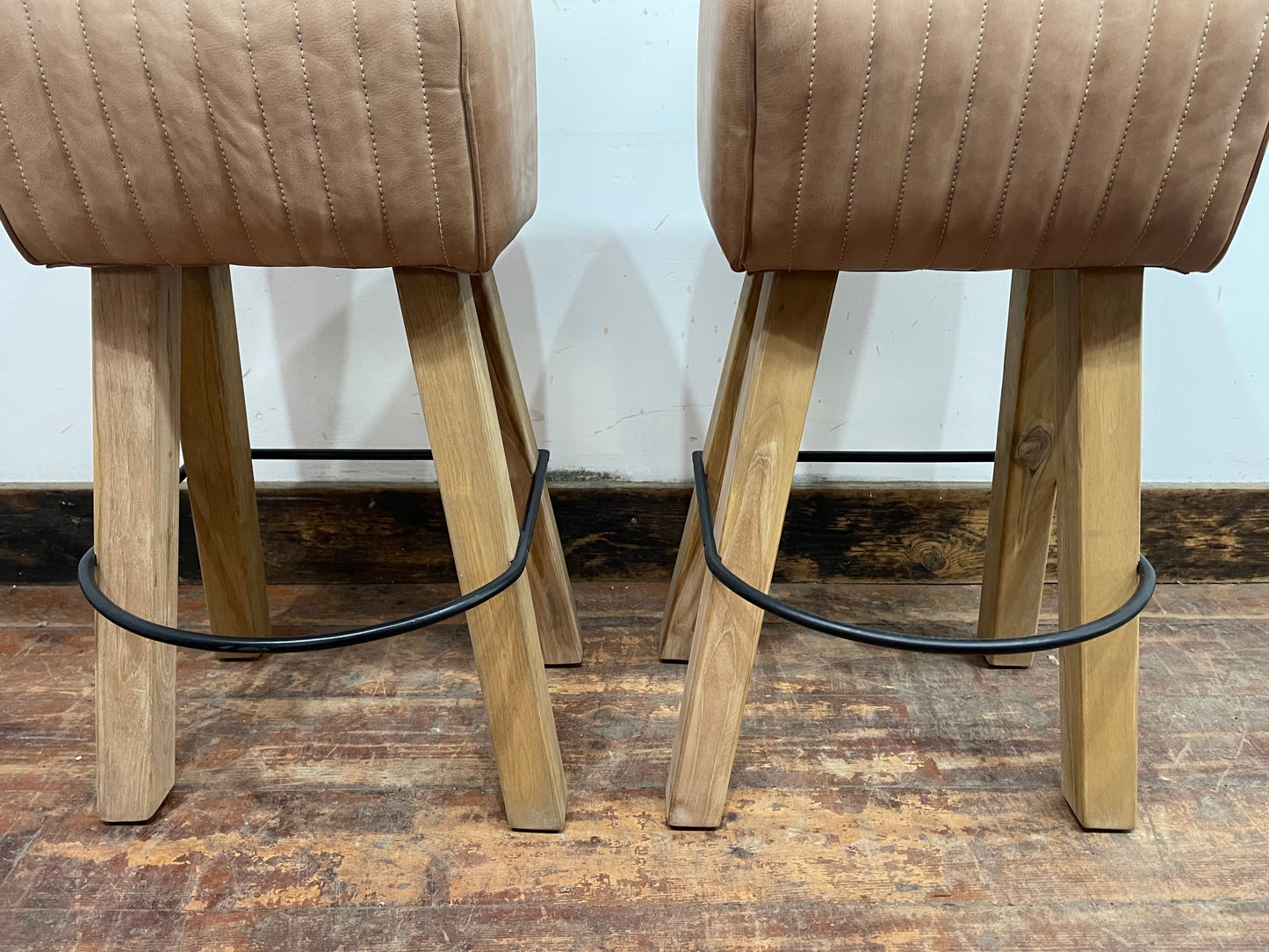 Pair of pommel stools with light tan leather seats
