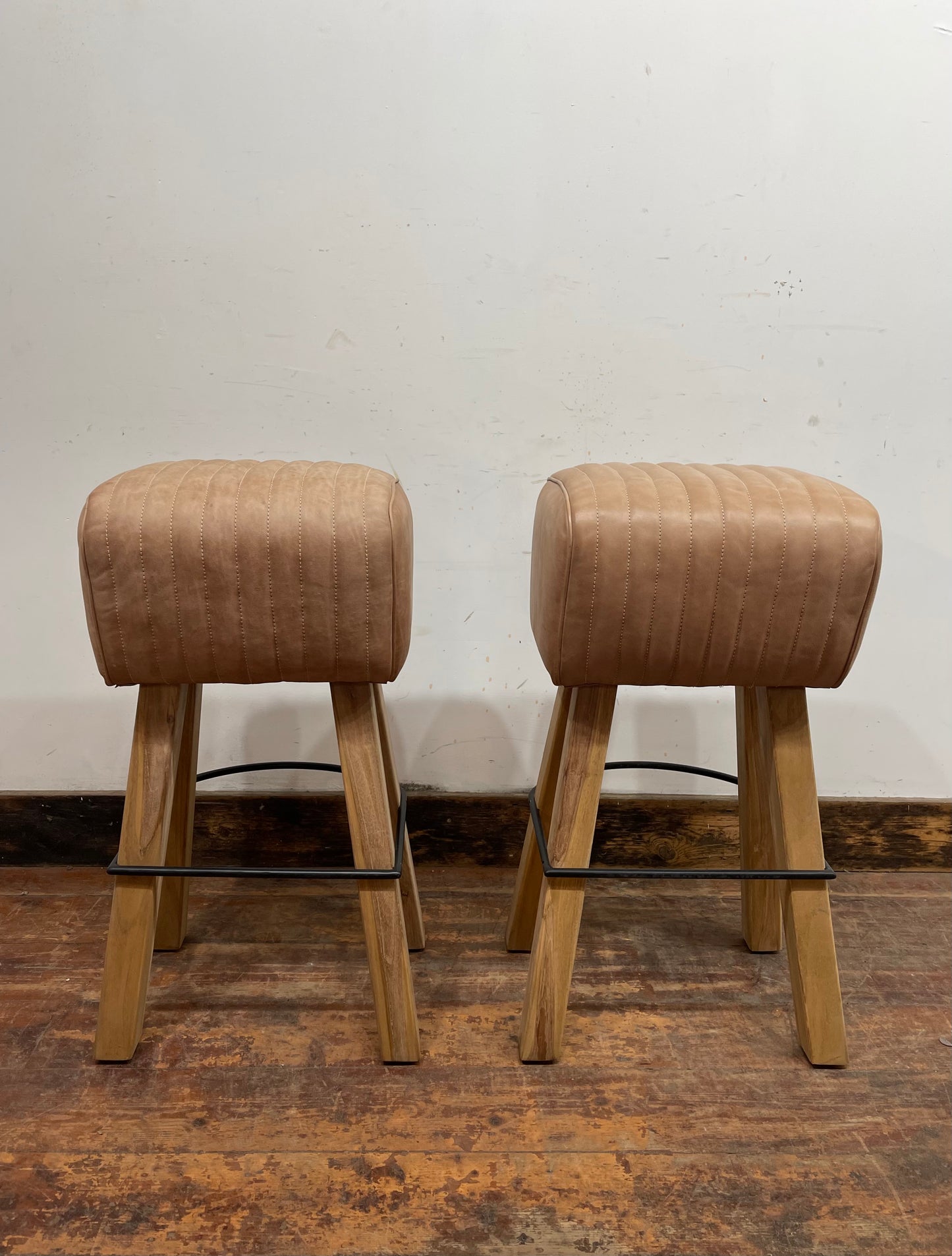 Pair of pommel stools with light tan leather seats