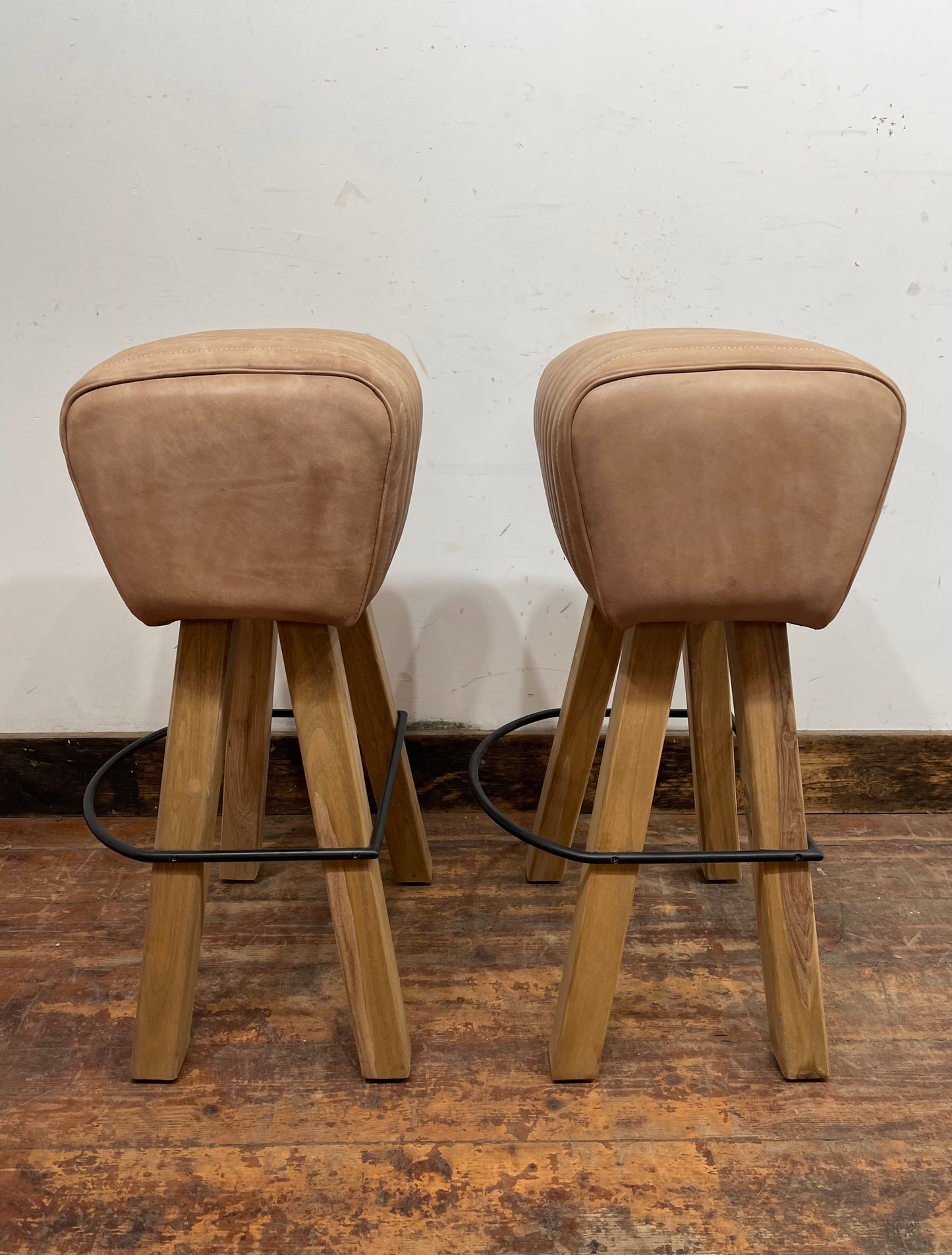 Pair of pommel stools with light tan leather seats