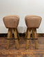 Pair of pommel stools with light tan leather seats